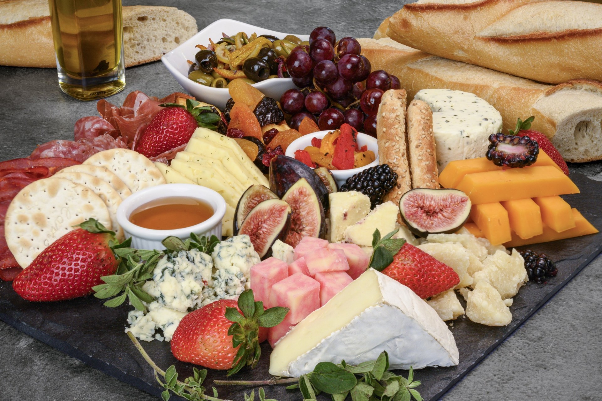 A platter of delicious fruits and cheeses with olives, cured meats and fresh bread.
