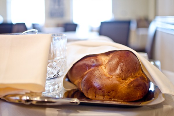 a loaf of challah bread is wrapped in an ivory linen napkin