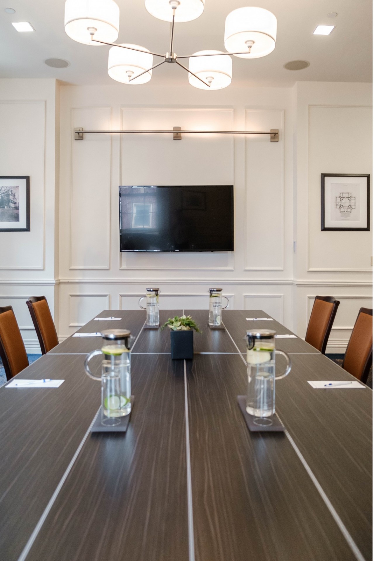 A flatscreen TV is mounted near the head of the table in the 1754 Boardroom