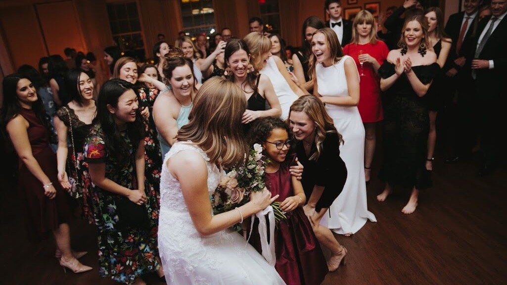 A bride hands her bouquet to a young girl