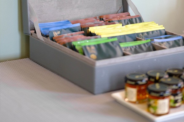 A gray linen box is open to display several flavors of bagged tea.