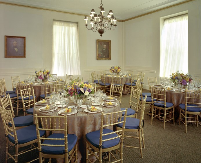 A room with a chandelier set for a banquet