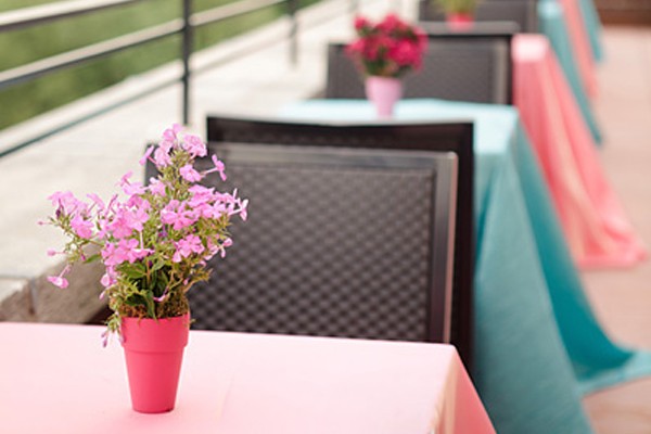 Tables for two are dressed with pastel pink and turquoise tablecloths on the Skyline Terrace.