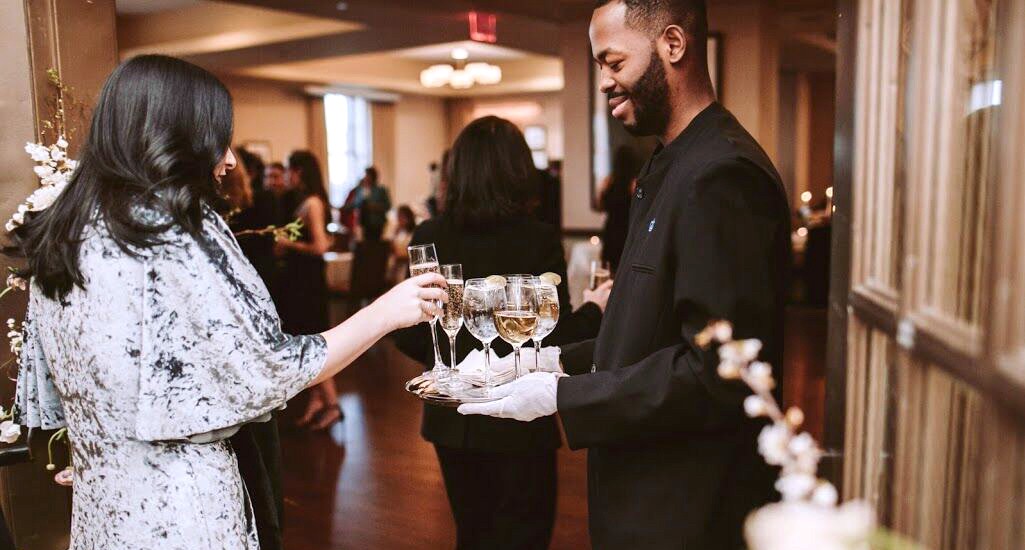 Invite guests to join in an elegant champagne toast. A woman accepts a glass of champagne from a server