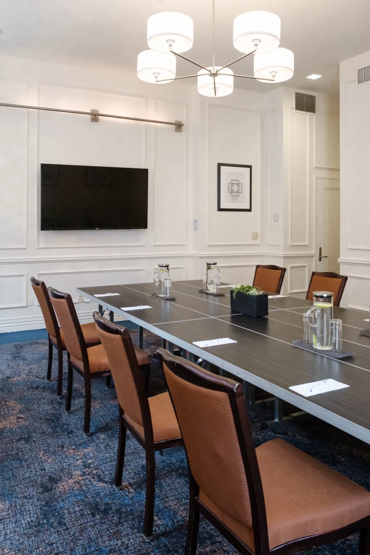 A flatscreen TV is mounted near the head of the table in the 1754 Boardroom