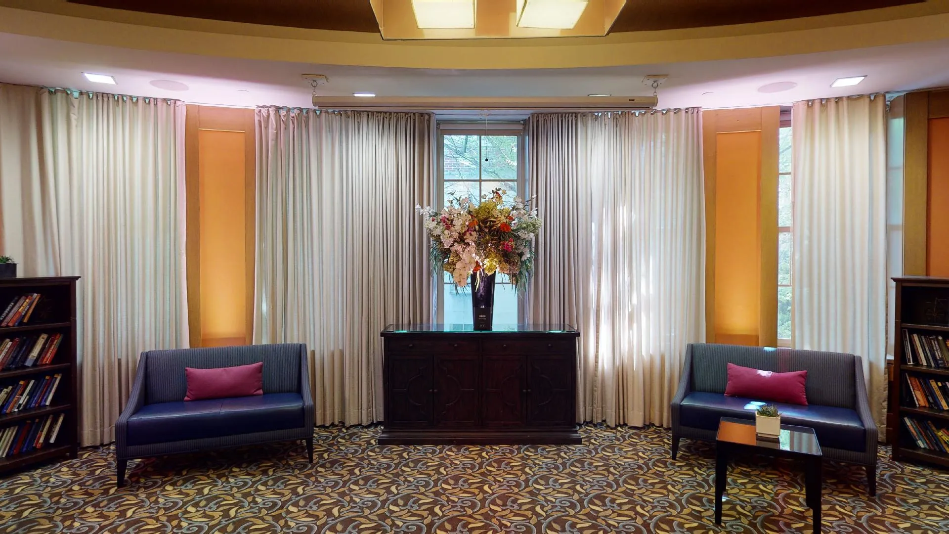 Love seats and bookshelves sit near windows in the Ivy Lounge