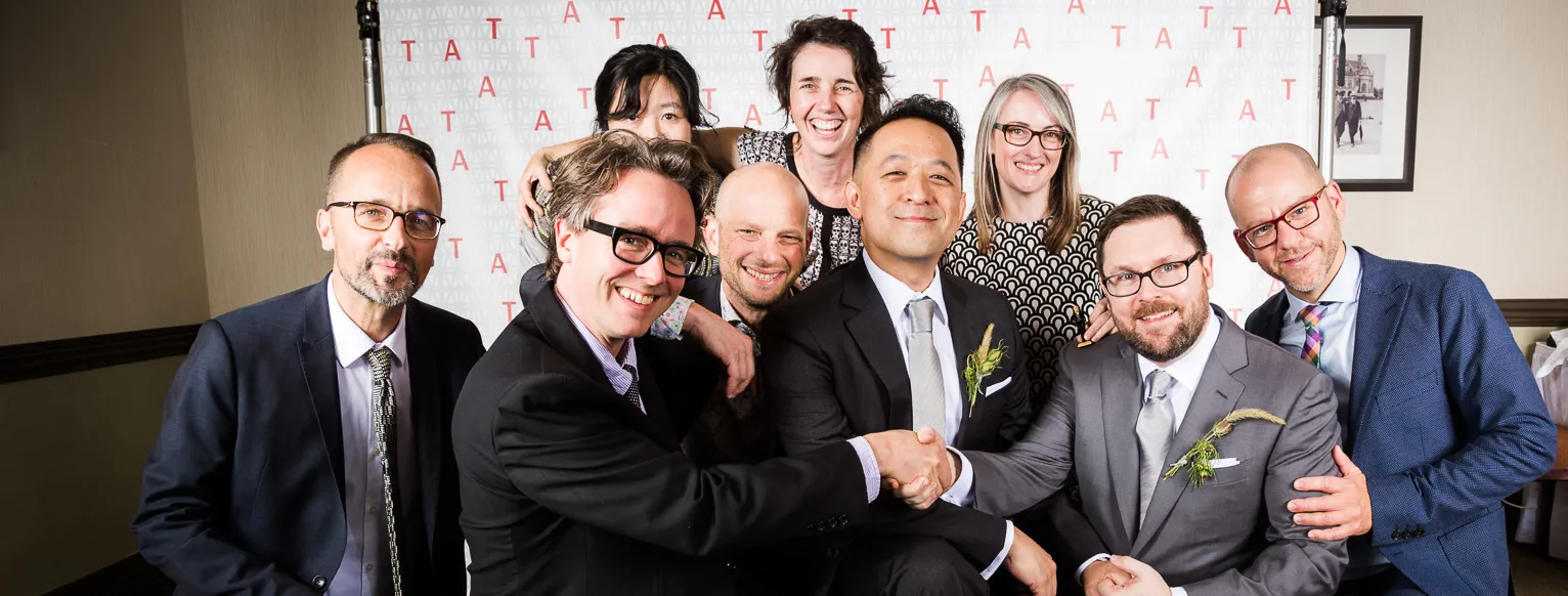 Newly married husbands pose for a photo with happy guests.