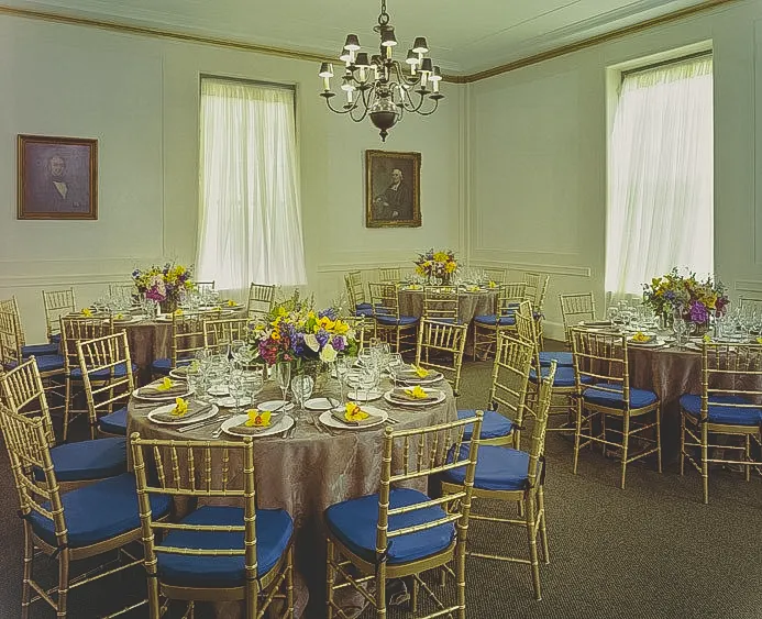 A room with a chandelier set for a banquet.