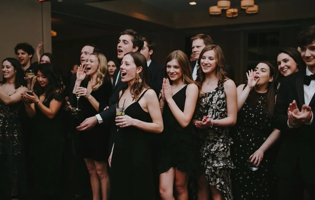 Guests dressed in formal wear stand together on the dance floor at Faculty House